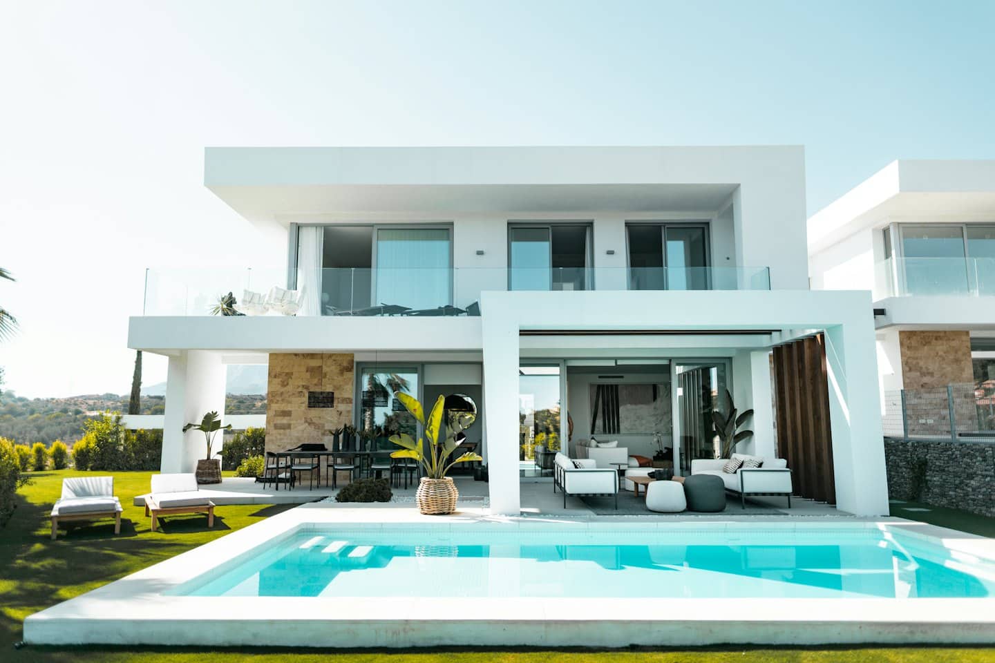 Villa moderna con piscina rettangolare e spazi living esterni.